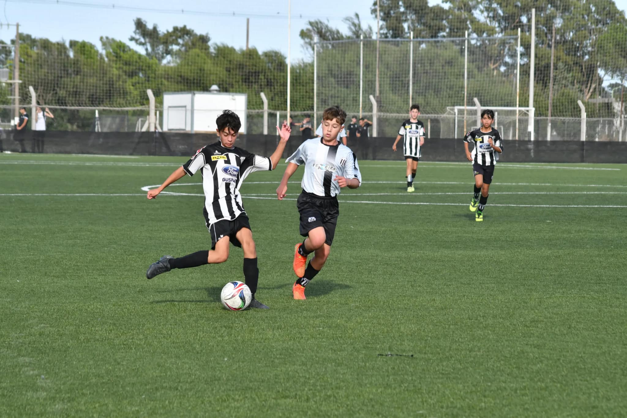 Chicos de las inferiores del Club Atlético Liniers disputan la pelota en la cancha de césped sintético del Complejo Oscar Zibecchi