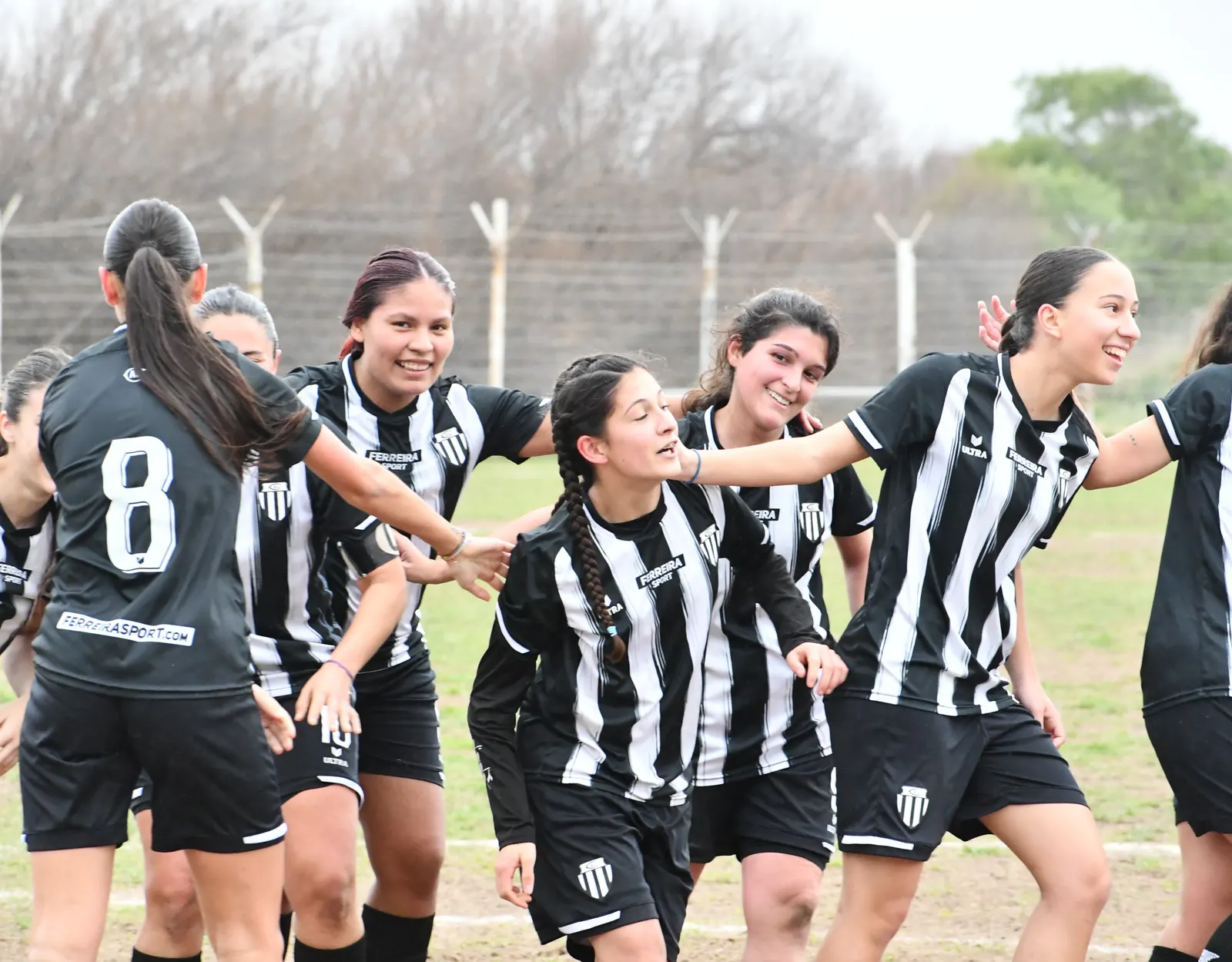 Jugadoras del fútbol femenino de Liniers se abrazan y festejan un gol en la cancha