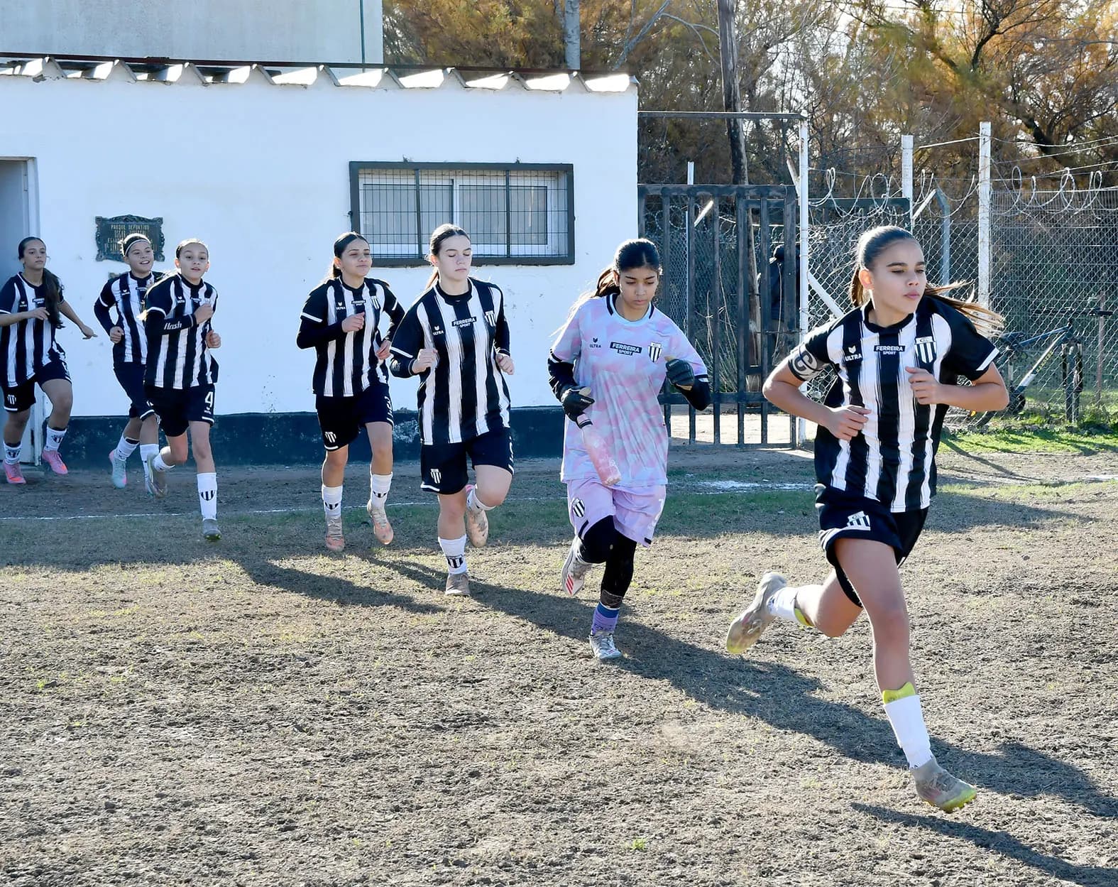 Las jugadoras de las inferiores de fútbol femenino de Liniers salen corriendo hacia la cancha