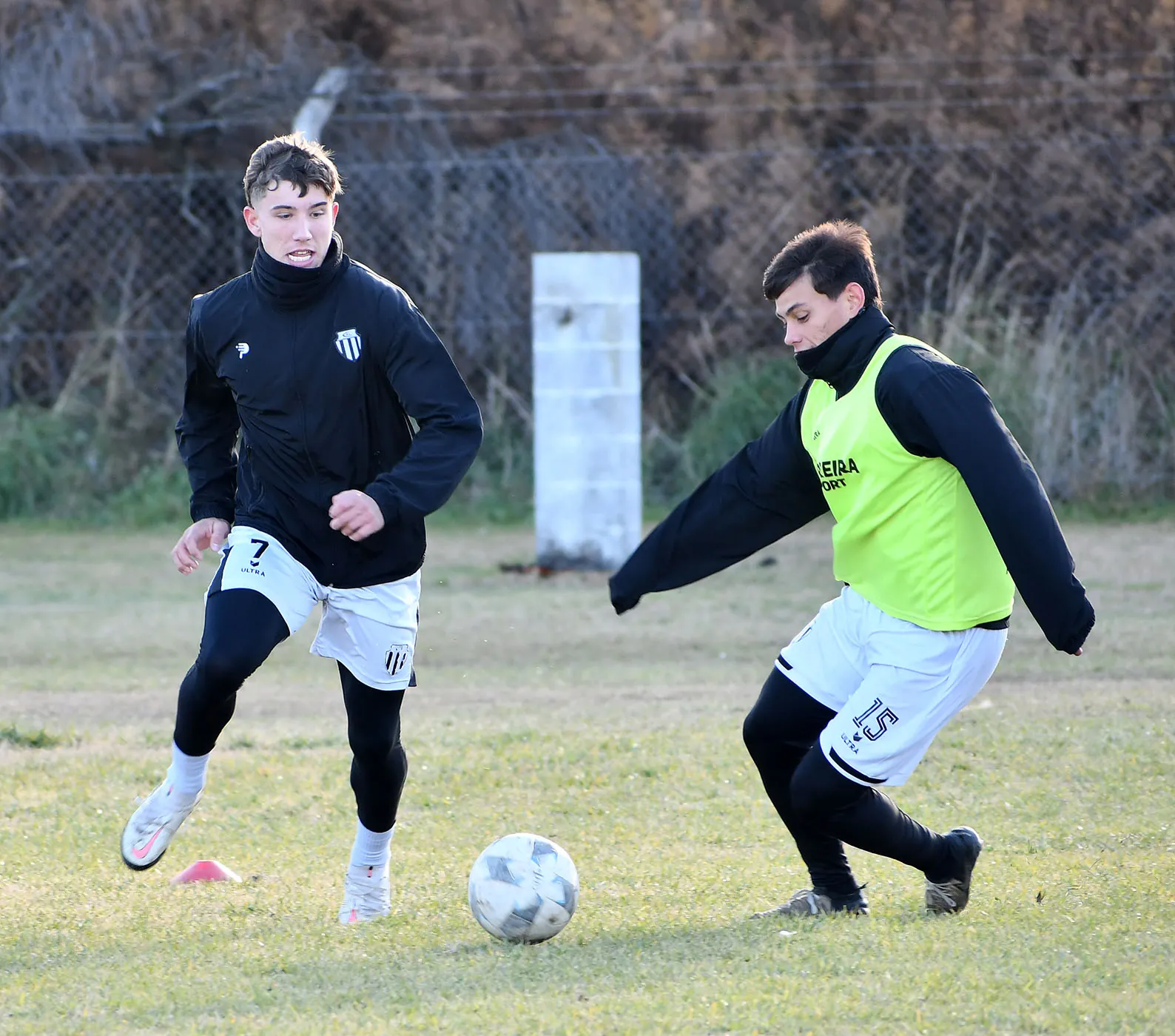 Dos jugadores entrenan sobre una cancha de césped natural del predio, con el terreno todavía castigado por la inundación