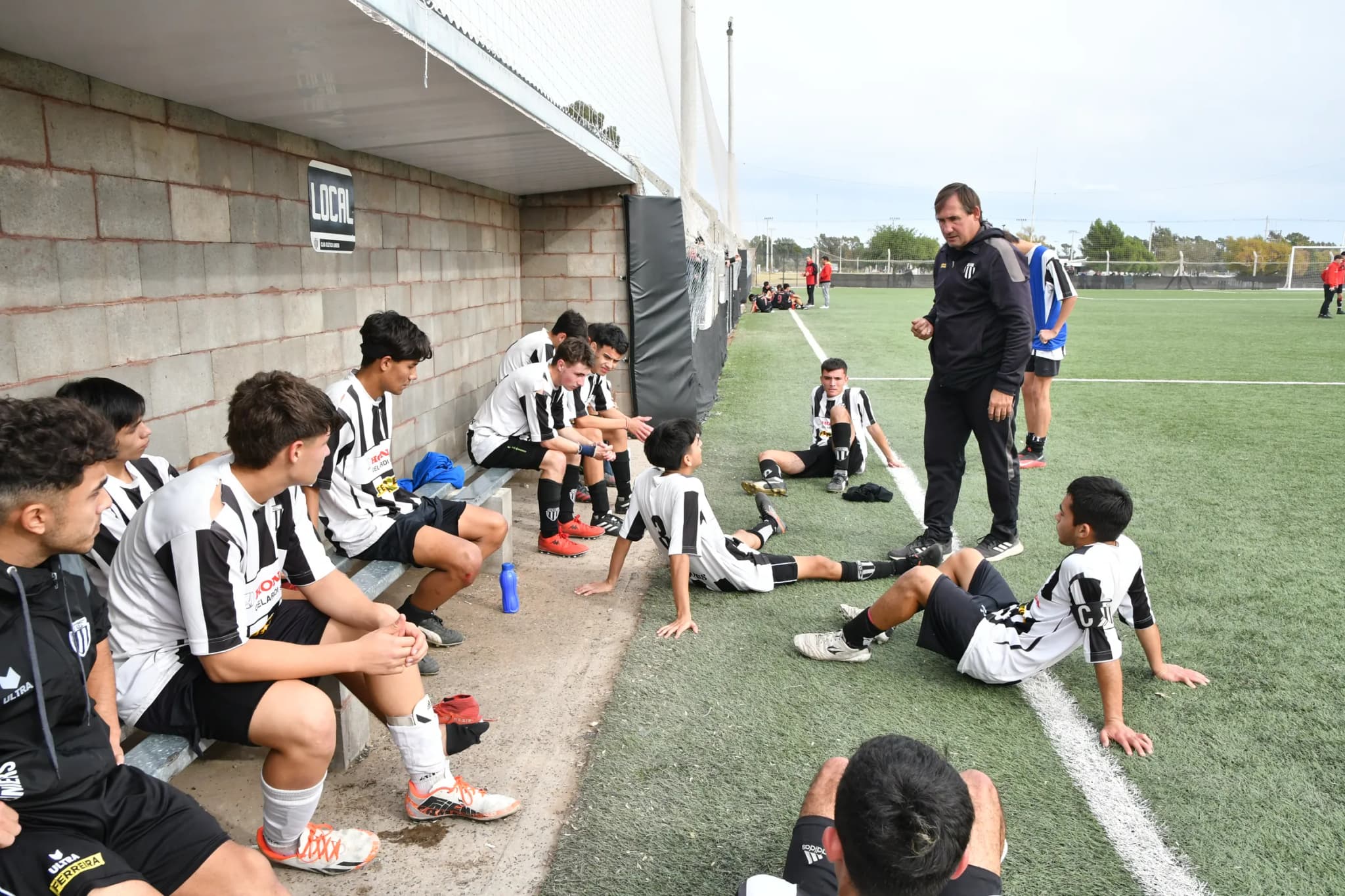 El entrenador da la charla a los chicos de las inferiores en el banco de suplentes del Complejo Oscar Zibecchi